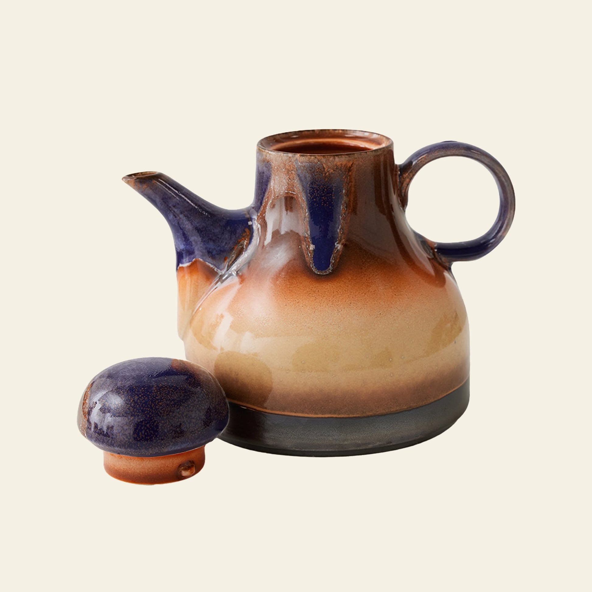 The HKLIVING 70s Ceramics: Coffee Pot - Afternoon features a rounded ceramic body, side handle, and spout in earthy brown and blue glazes. The matching lid sits in front on a beige background, reflecting HKLIVING’s subtle 1970s-inspired style.