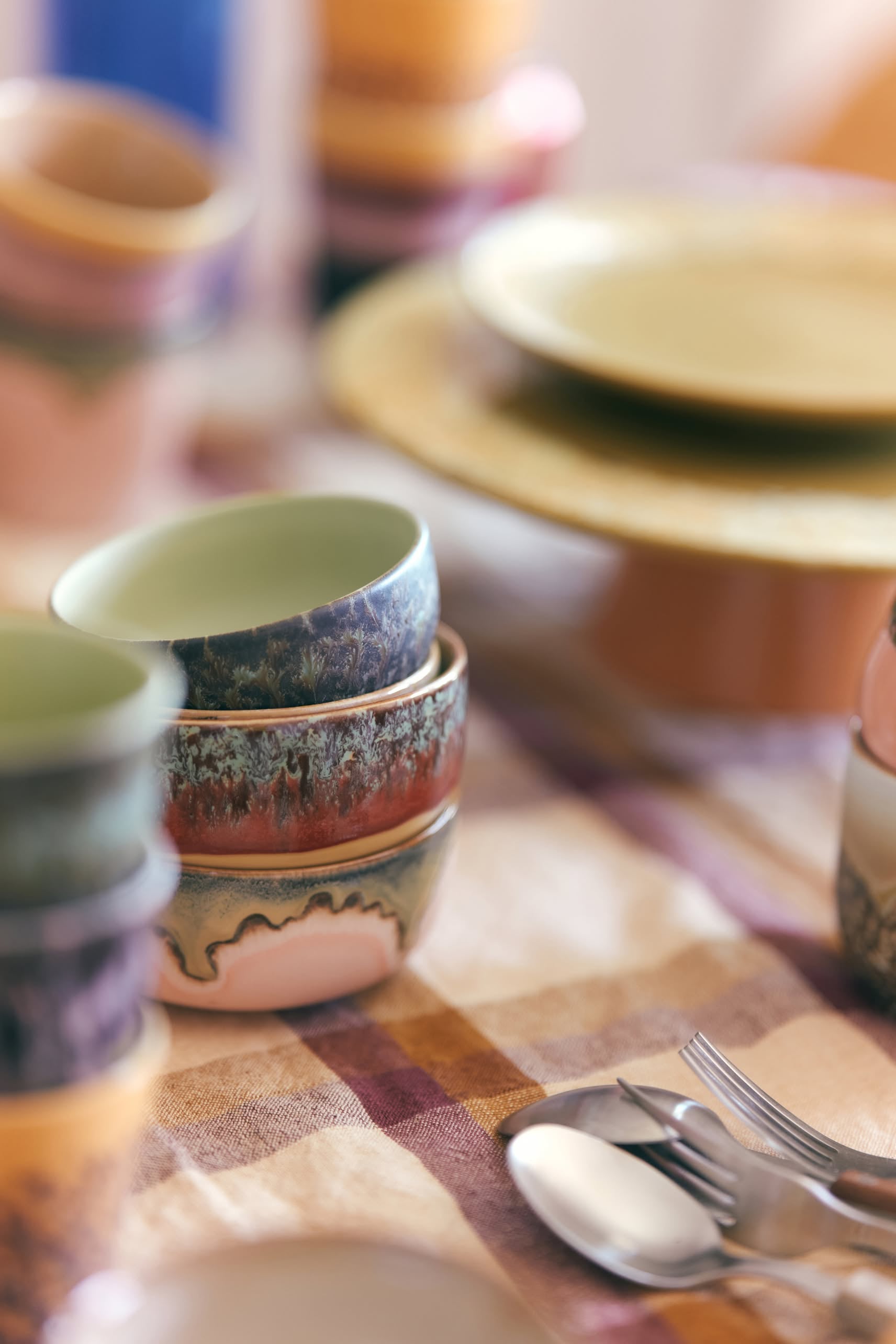 The HKLIVING 70s Ceramics Dessert Bowls, Set of 4, feature colorful retro patterns inspired by 70s design, bringing a cozy and inviting touch to your table alongside plates, cups, and cutlery.