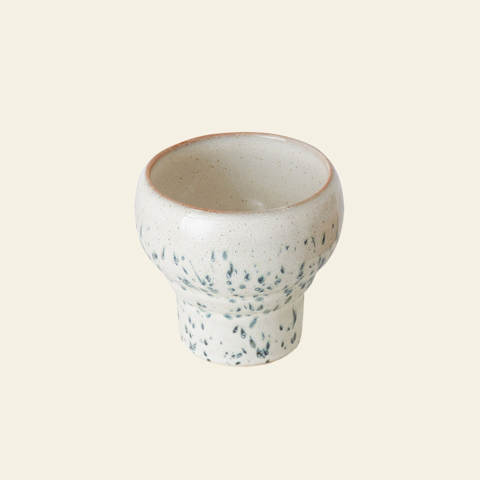 The HKLIVING 70s Ceramics: Lungo Mugs, Set of 2, features small ceramic cups with a rounded top, narrow base, speckled off-white glaze, and subtle green accents, inspired by vintage mugs and set against a plain beige background.