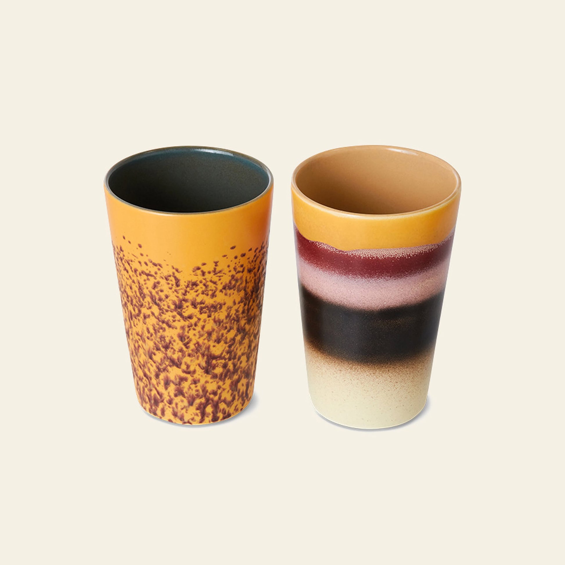 The HKLIVING 70s Ceramics: Tea Mugs, Set of 2 features one yellow mug with brown speckles and another with tan, burgundy, black, and cream bands—bringing retro style to your collection.