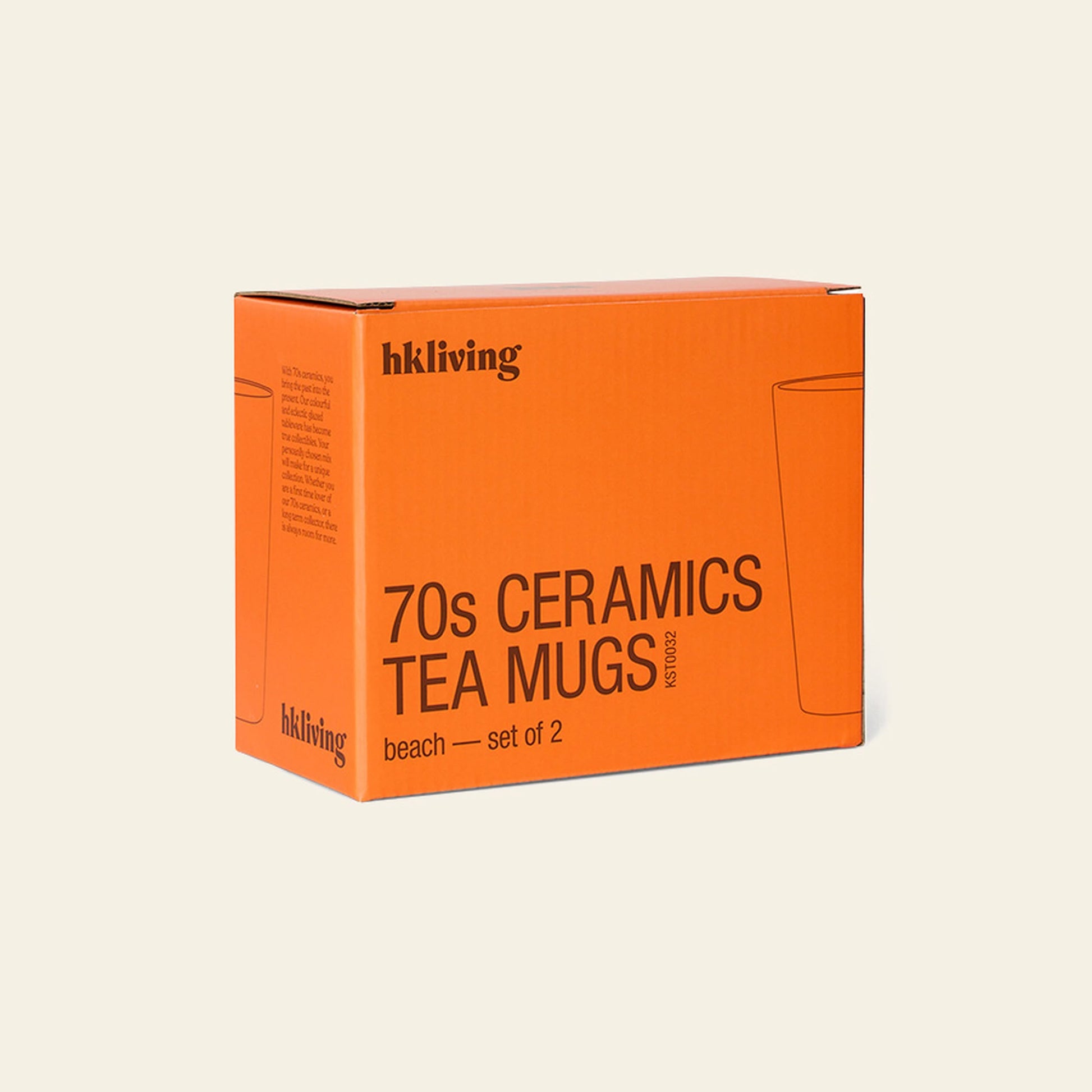 An orange box labeled HKLIVING 70s Ceramics: Tea Mugs, Set of 2 sits against a plain light background, with minimalist packaging that highlights the HKLIVING brand name, simple text, and a subtle mug outline on the box.
