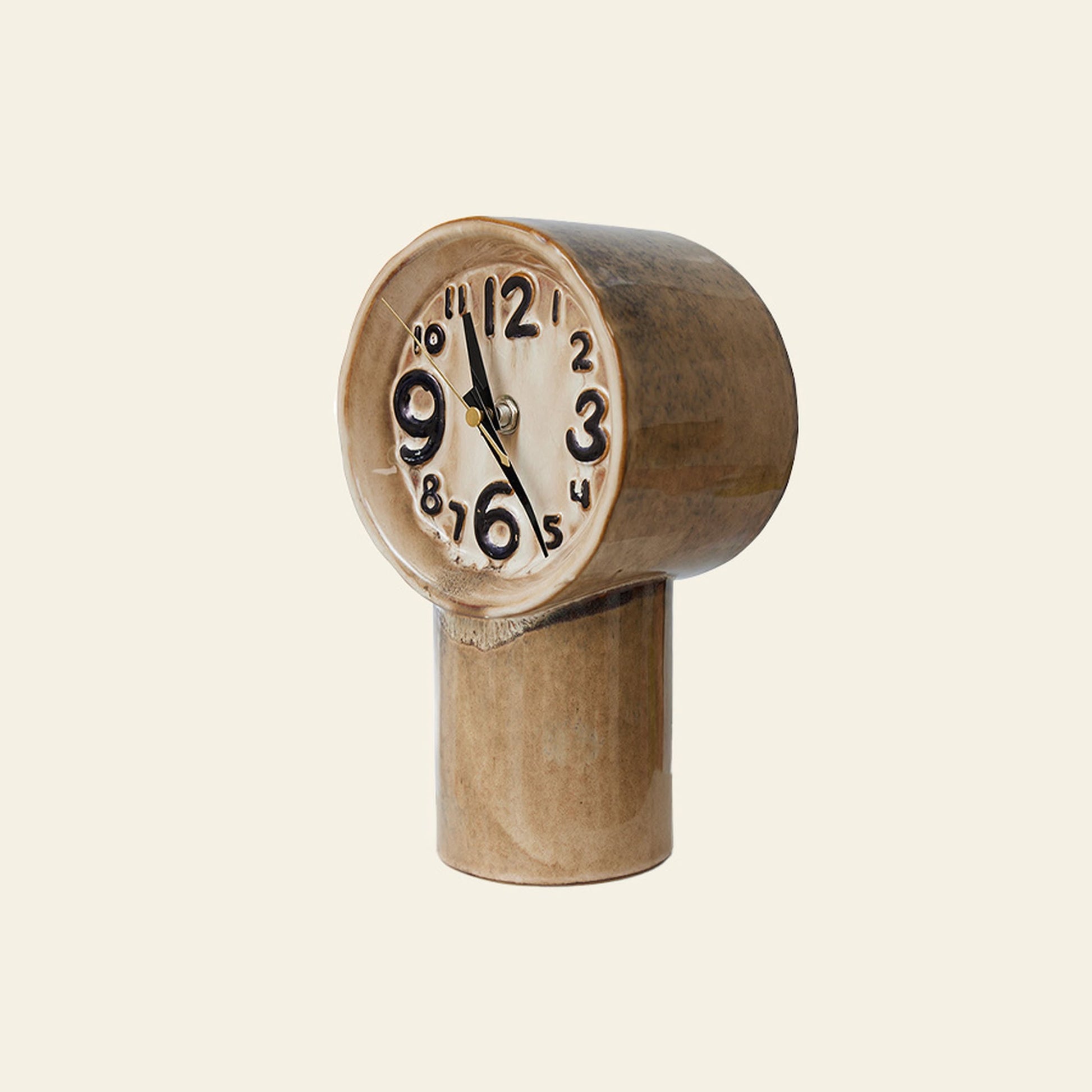 The HKLIVING Retro Ceramic Clock - Cream by HKLIVING features a distorted face with exaggerated numbers and vintage-inspired design, mounted on a cylindrical base and shown against a simple, light background.