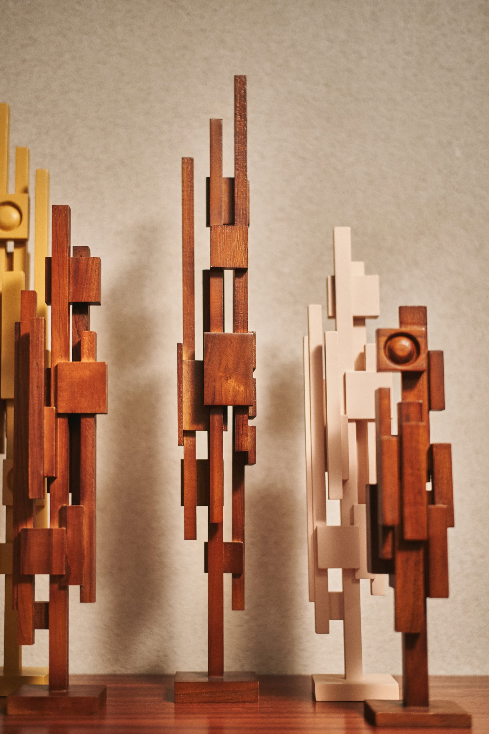 The HKLIVING Skyline Sculpture S - Espresso by HKLIVING features intersecting rectangular and square teak blocks in brown, beige, and tan hues, standing upright on a wooden surface for an urban-inspired look against a neutral background.