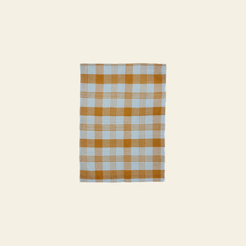 The HKLIVING Vida Check Tea Towel in Amber/Blue features a rectangular linen design with a light blue and mustard yellow checkered pattern on a plain, light beige background.