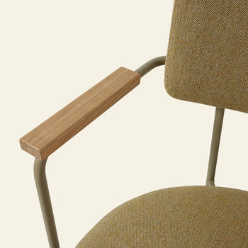 Close-up of the HKLIVING Dining Armchair in Main Line Flax Olive, featuring textured olive upholstery, a metal frame, and wooden armrests, inspired by Dutch design and set against a light background.