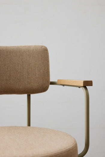 A close-up of the HKLIVING Dining Armchair, Main Line Flax in Olive, featuring a beige fabric seat and backrest, light metal frame, and wooden armrests—showcasing refined Dutch design by HKLIVING against a plain light gray background.