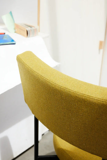 An HKLIVING Dining Chair, Main Line Flax in black, sits by a white desk topped with books and papers, set against a light wall in a modern, minimalistic room.
