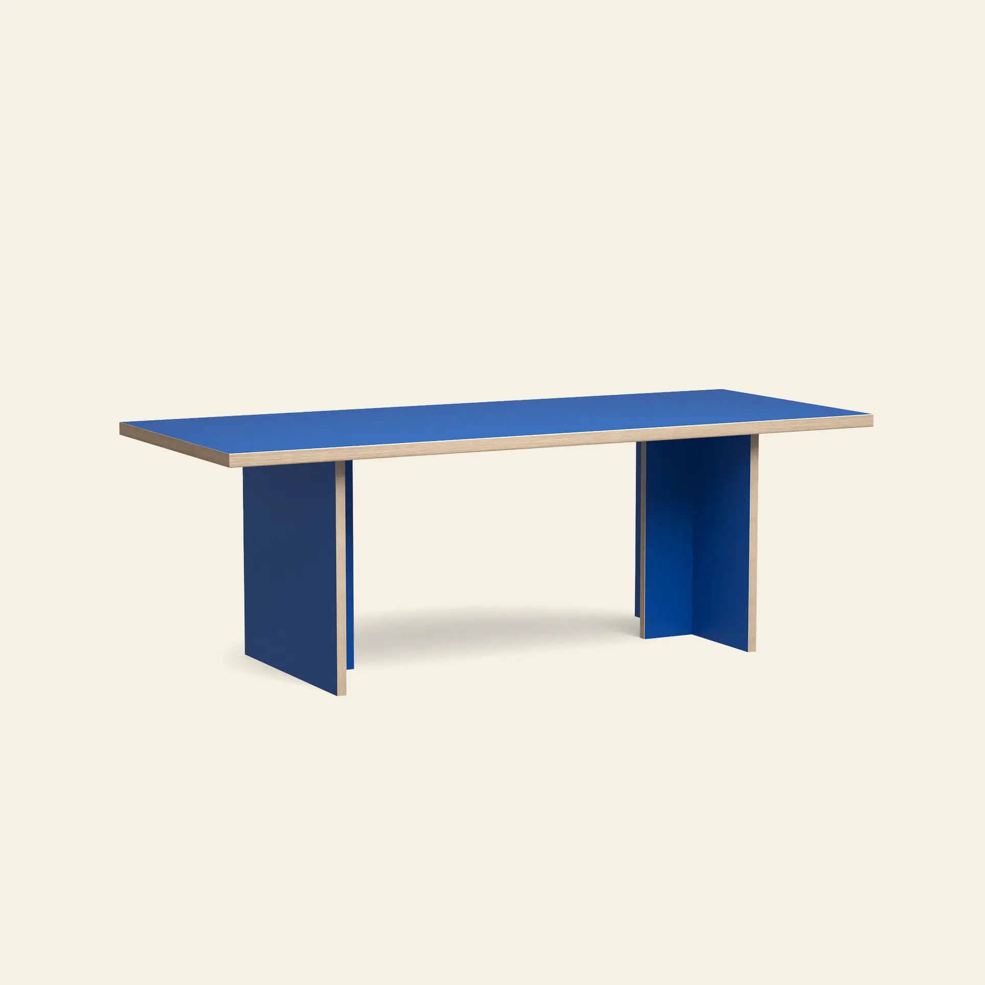The HKLIVING Dining Table, Rectangular, 220cm features a bright blue top and panel legs with exposed wood edges, creating a modern look against a plain light background.