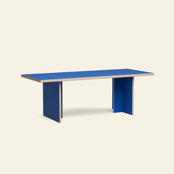 The HKLIVING Dining Table, Rectangular, 220cm features a bright blue top and panel legs with exposed wood edges, creating a modern look against a plain light background.