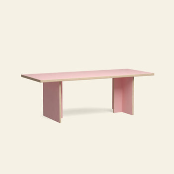 The HKLIVING Dining Table, Rectangular, 220cm by HKLIVING features light wood edges, flat pink surfaces, and two wide legs at each end—a minimalist piece that stands out against a plain beige background.