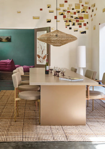 A modern dining room features the HKLIVING Dining Table, Rectangular, 280cm by HKLIVING, six beige chairs, a woven pendant light, wine glasses and bottle, an open book, colorful square wall decor, and a textured beige rug for a timeless look.
