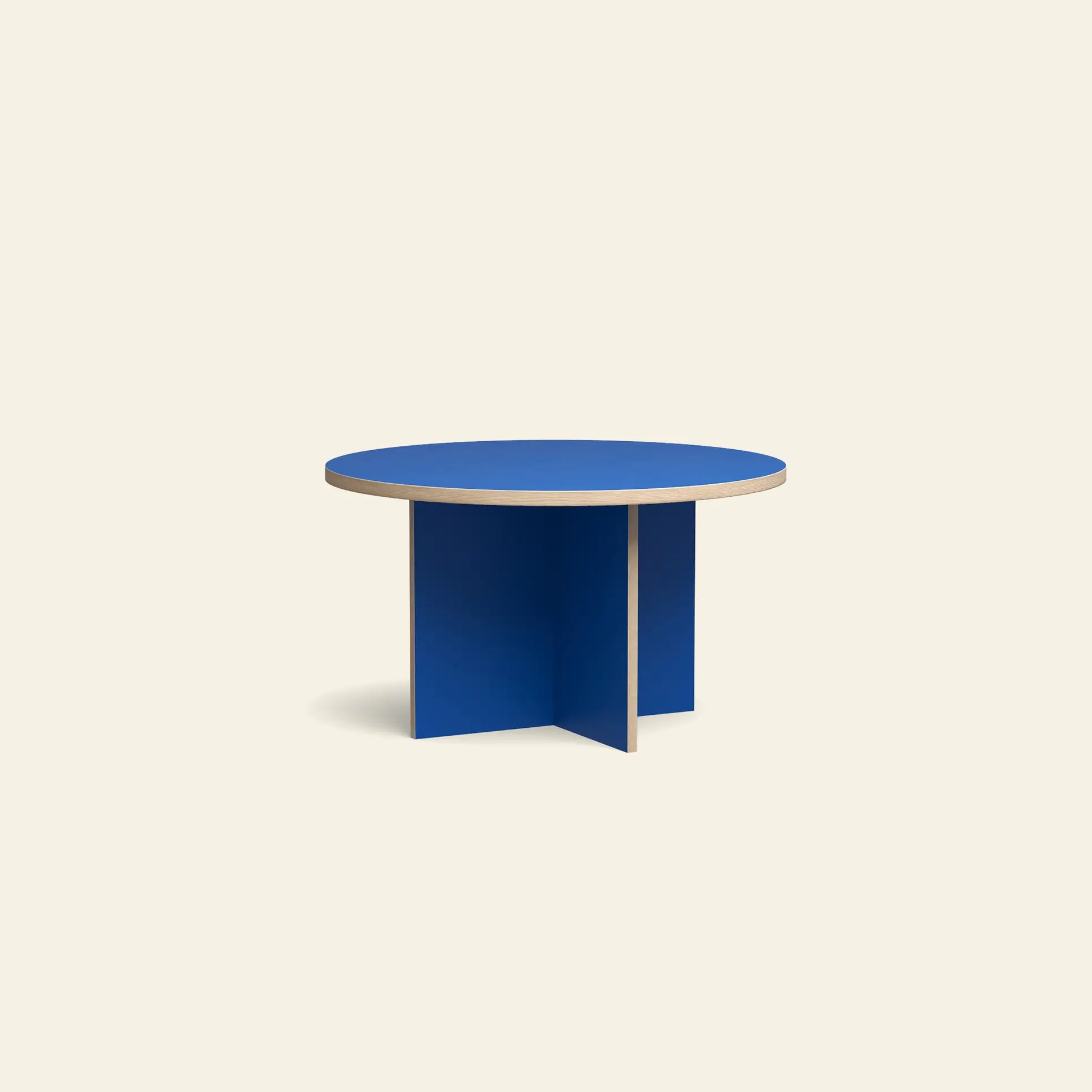 The HKLIVING Dining Table, Round, 130cm by HKLIVING features a blue top, wooden edge, and unique intersecting base, set against a plain light beige background.