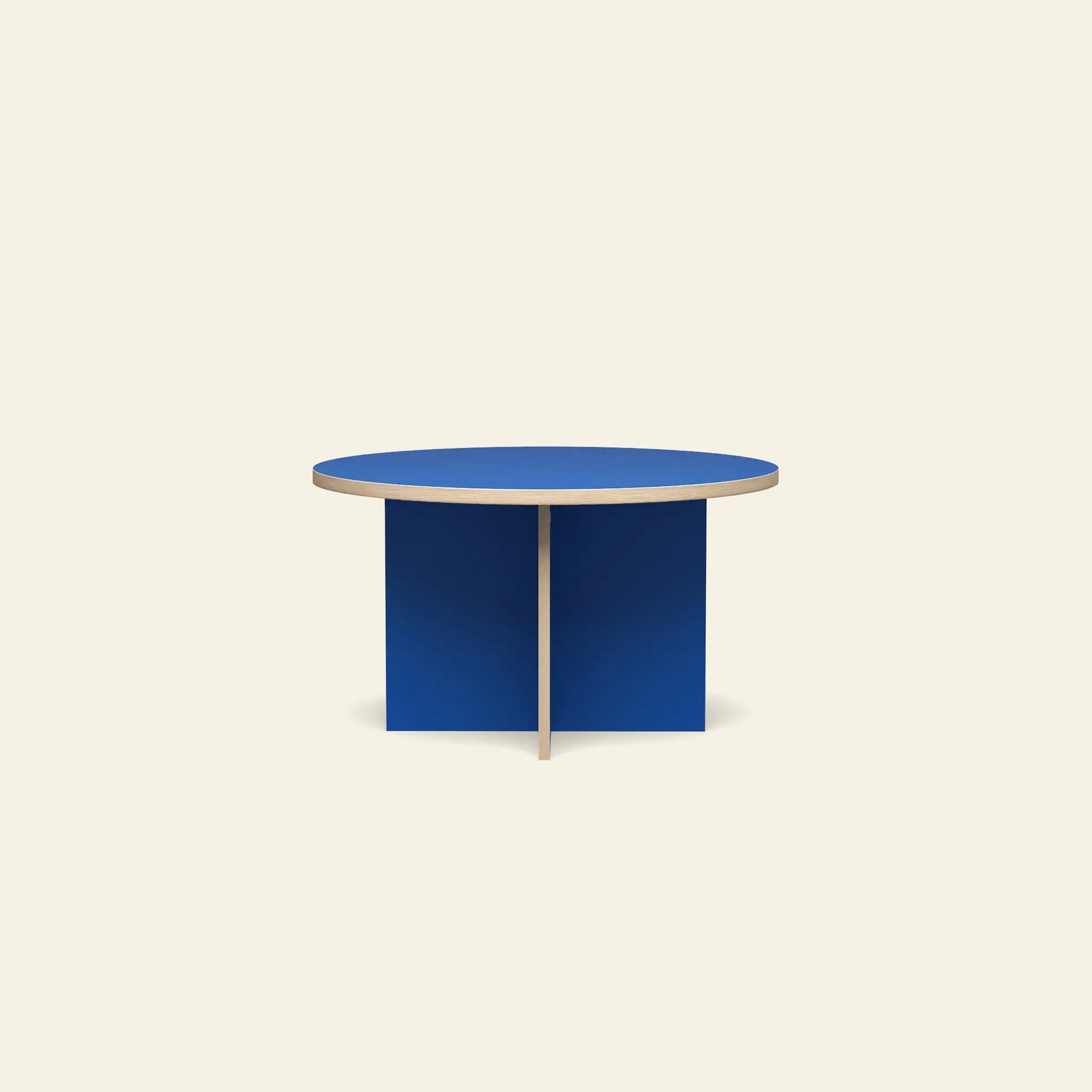 The HKLIVING Dining Table is a modern round 130cm table with a blue top and intersecting base panels, standing out against an off-white background.