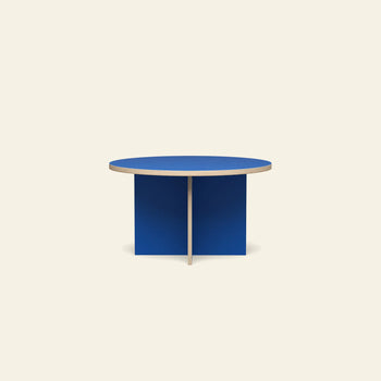 The HKLIVING Dining Table is a modern round 130cm table with a blue top and intersecting base panels, standing out against an off-white background.