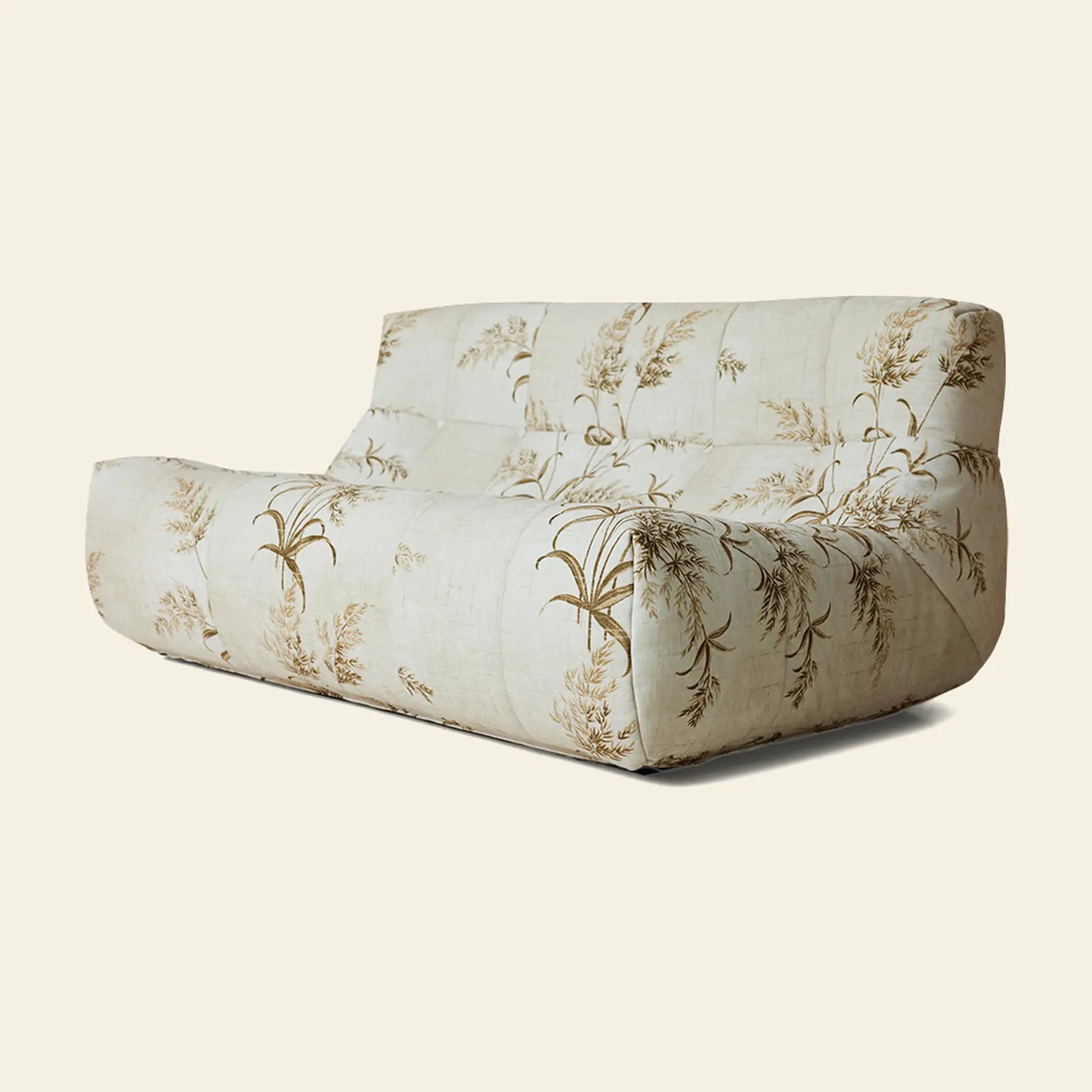 The HKLIVING Lazy Lounge Bench by HKLIVING is a modern, low-profile sofa featuring a tufted back and seat, upholstered in cream fabric with a subtle brown botanical pattern on a plain light background.