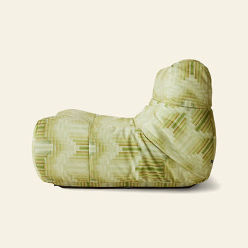 The HKLIVING Lazy Lounge Chair by HKLIVING features a soft, relaxed shape and cushioned high backrest, shown in profile. Its geometric pixelated pattern comes in playful green prints against a plain beige background.