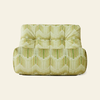 The HKLIVING Lazy Lounge Chair by HKLIVING features a vintage-inspired armless design with a tufted back and seat, upholstered in green and beige geometric prints on a cream background.