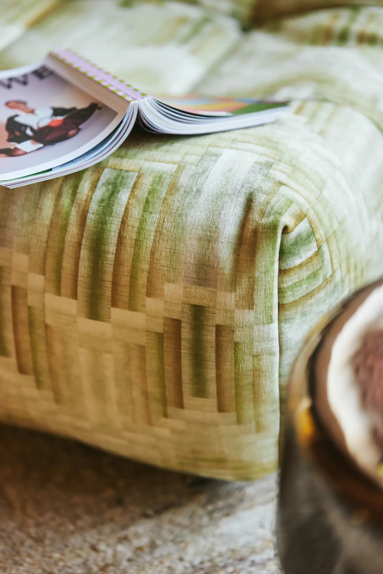 A close-up of the HKLIVING Lazy Lounge Chair showcases playful green upholstery with an open magazine on top, set against a soft textured rug and part of a round wooden table in the background.