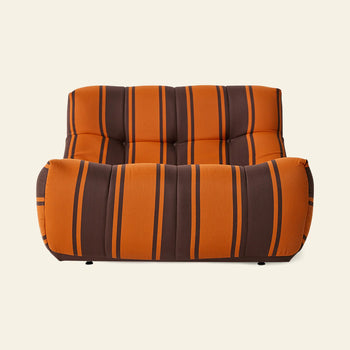 The HKLIVING Lazy Lounge Chair Outdoor by HKLIVING features wide orange and brown vertical stripes, a low profile, and tufted seat and backrest, shown against a plain off-white background.