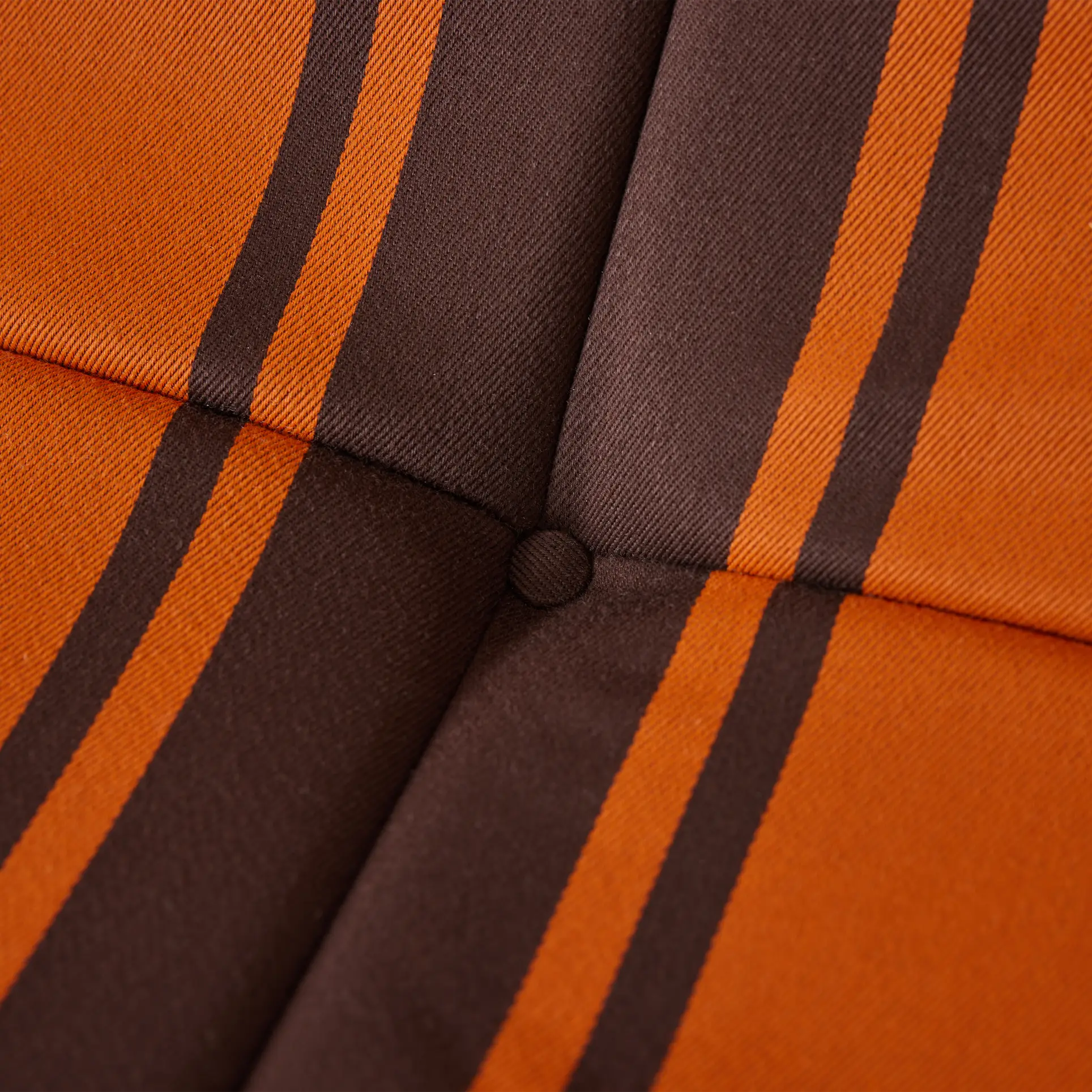Close-up of the HKLIVING Lazy Lounge Chair Outdoor by HKLIVING, showing an upholstered cushion with orange and brown vertical stripes, intersecting at a button-tufted center. The fabric has a textured look.