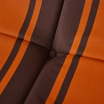 Close-up of the HKLIVING Lazy Lounge Chair Outdoor by HKLIVING, showing an upholstered cushion with orange and brown vertical stripes, intersecting at a button-tufted center. The fabric has a textured look.