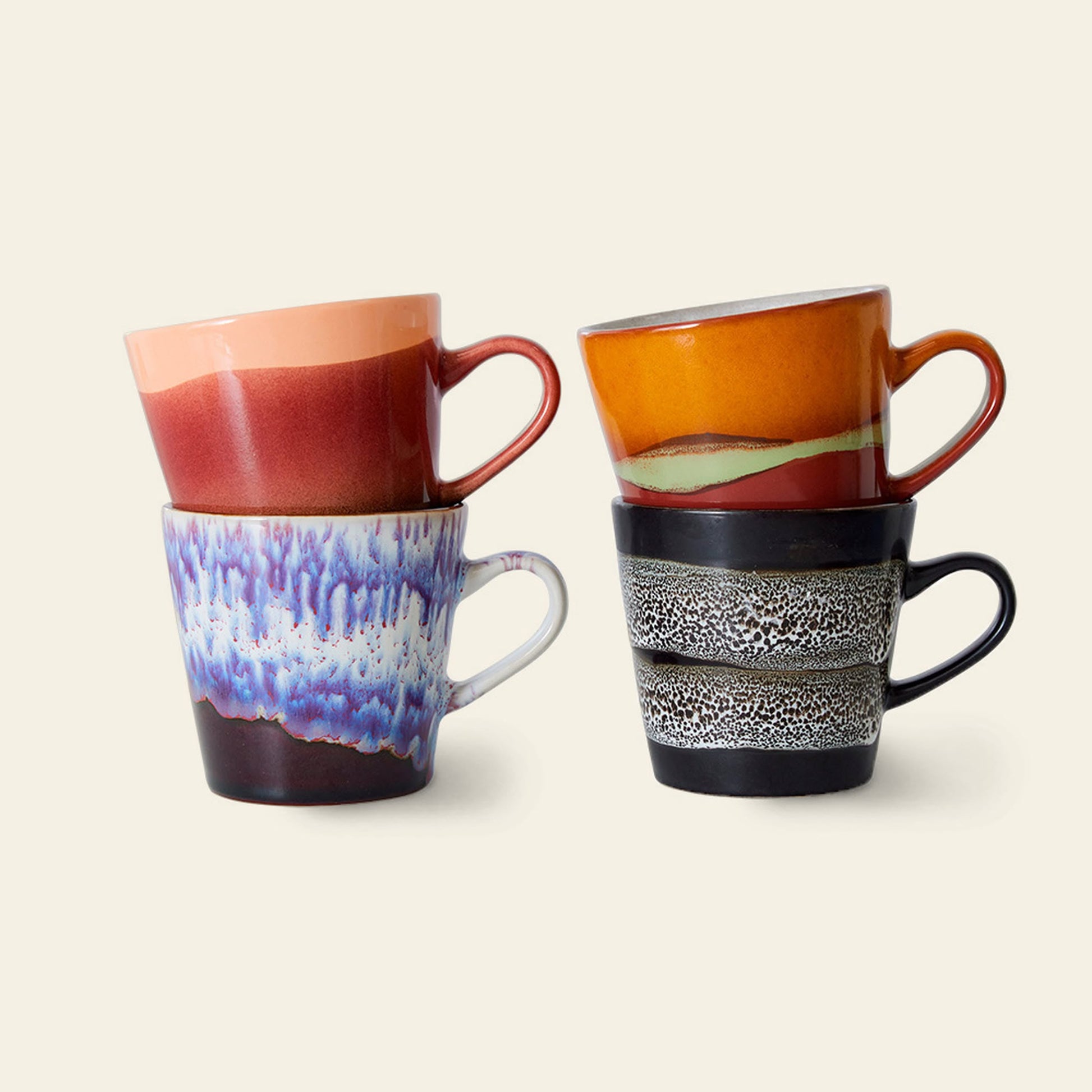 The HKLIVING 70s Ceramics: Americano Mugs, Set of 4 features hand-glazed stoneware mugs in colorful pairs—red/peach, wavy orange, blue/purple, and black with a white band—reflecting vibrant 70s style.