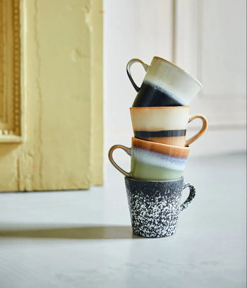Four HKLIVING 70s Ceramics: Americano Mugs, Set of 4 are stacked in a tower on a light surface, highlighting their hand-glazed stoneware and vintage-inspired designs; a yellow frame appears in the background.
