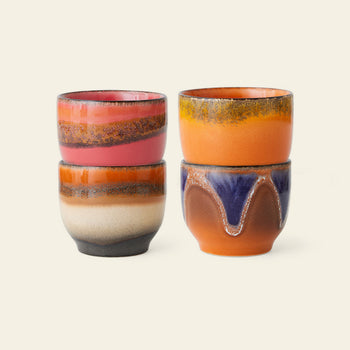 The HKliving 70s Ceramics: Café Cups, Set of 4 - Java features retro coffee cups with colorful glazed designs in pink, orange, brown, blue, and purple, stacked in pairs against a light beige background.