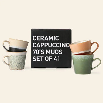Four hand-glazed cappuccino mugs in different colors from the HKLIVING 70s Ceramics: Cappuccino Mugs, Set of 4 are stacked in pairs beside a black HKLIVING box, all shown against a light beige background.