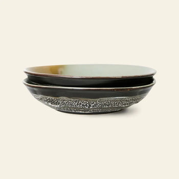 The HKliving 70s Ceramics: Curry Bowls, Set of 2, features shallow, round bowls with dark exteriors and textured speckled designs, adding a vintage touch to your table.