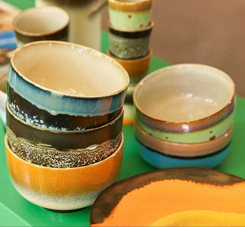 HKLIVING 70s Ceramics: Dessert Bowls, Set of 4—colorful retro-glazed bowls in orange, blue, green & brown—stacked on a green surface with matching plates and cups by HKLIVING.