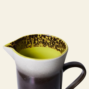 The HKLIVING 70s Ceramics: Jug - Bomb features a wide spout and handle, a dark brown to light gray gradient, yellow interior, and speckled rim—a perfect retro-inspired ceramic pitcher.