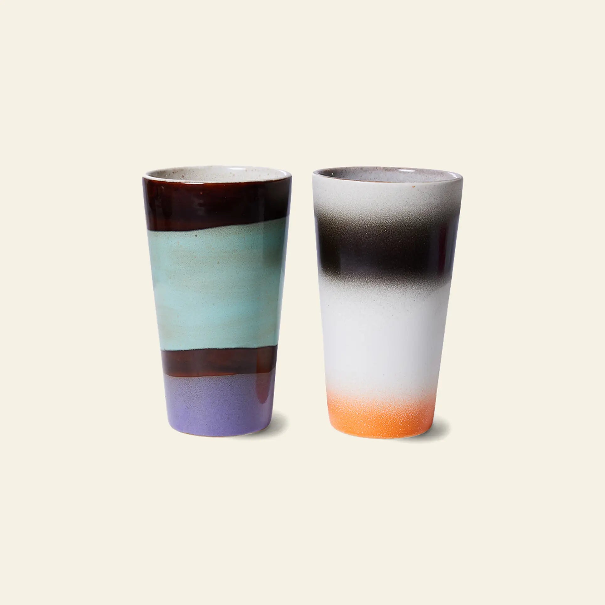 The HKLIVING 70s Ceramics: Latte Mugs, Set of 2 features tall ceramic cups with handcrafted glazes—one with brown, blue-green, and purple bands; the other with a white, black, and orange gradient—perfect for retro mug collections.