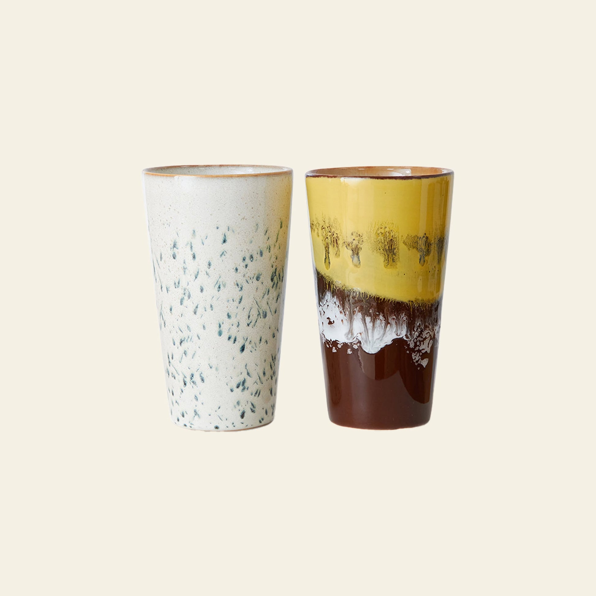 HKLIVING 70s Ceramics: Latte Mugs, Set of 2 by HKLIVING—includes one mug with a white handcrafted glaze and green speckles, and another with glossy yellow, brown, and white layers—displayed against a plain light background.