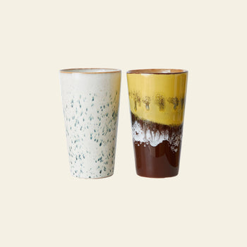HKLIVING 70s Ceramics: Latte Mugs, Set of 2 by HKLIVING—includes one mug with a white handcrafted glaze and green speckles, and another with glossy yellow, brown, and white layers—displayed against a plain light background.