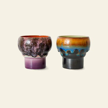 The HKLIVING 70s Ceramics Lungo Mugs Set of 2 features retro ceramic cups: one with a purple and dark maroon glaze, the other in orange, blue, and brown with a drip effect—perfect for vintage coffee style.