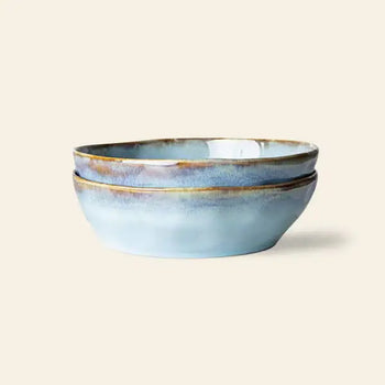 The HKliving 70s Ceramics: Pasta Bowls, Set of 2, by HKliving, features blue and brown glazed bowls stacked together on a light beige background—perfect for an elegant table setting.