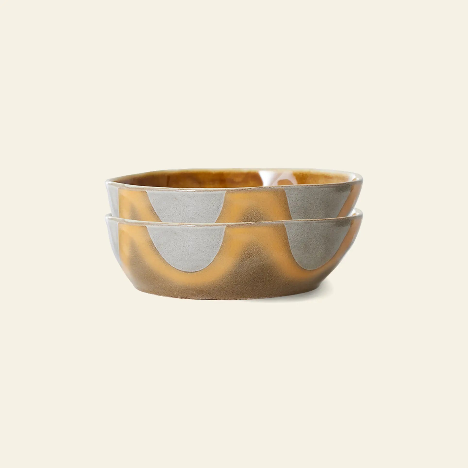 Two stacked HKliving 70s Ceramics Pasta Bowls, Set of 2, display a wavy abstract pattern in matte gray and glossy ochre brown—ideal for an elegant table setting on a light beige background.