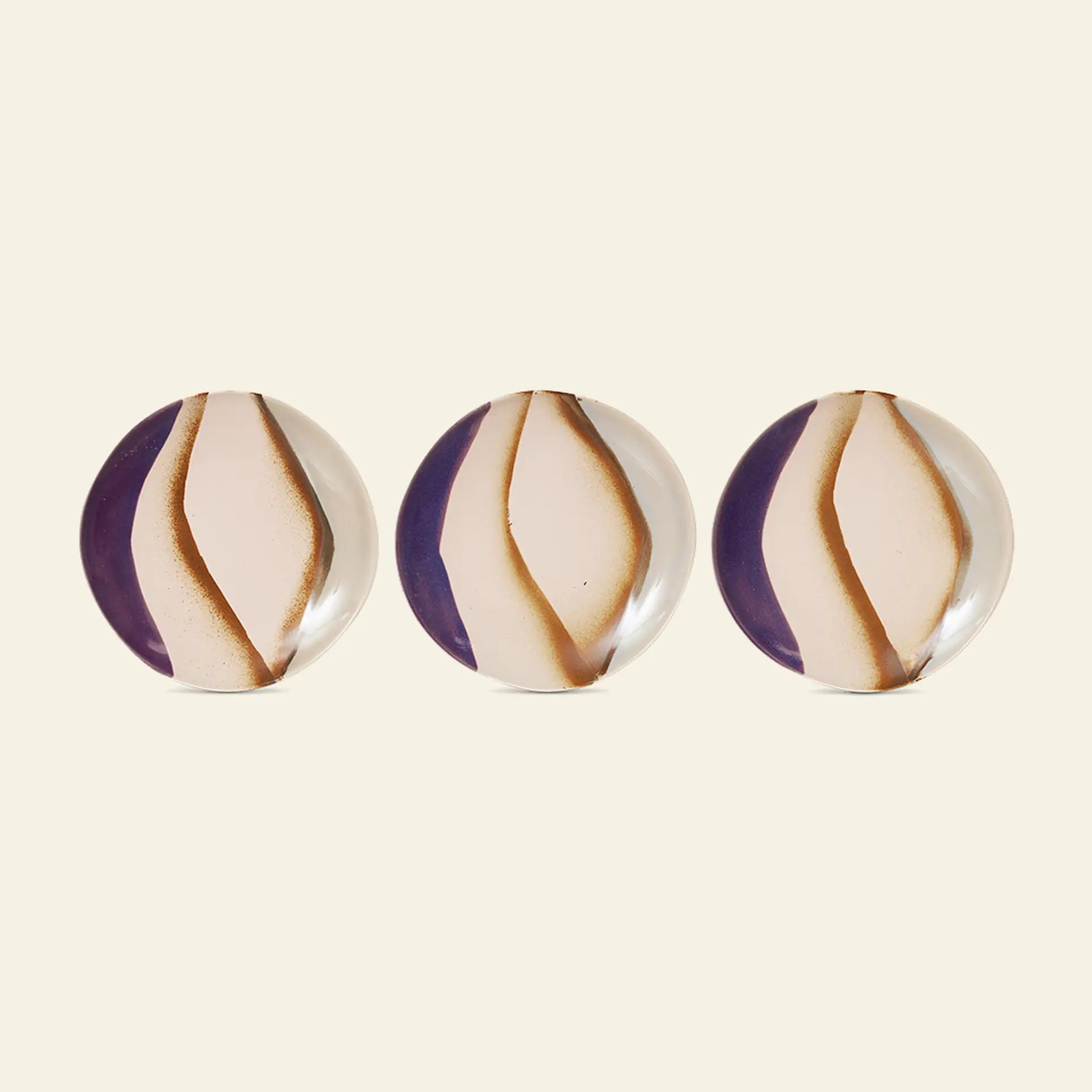 Two HKLIVING 70s Ceramics side plates, featuring a white and brown swirl pattern, are displayed in a row on a plain light beige surface against a purple background.