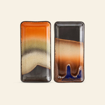 The HKLIVING 70s Ceramics: Small Trays, Set of 2 – Twenty Four Hours features two rectangular ceramic trays with glossy, bold gradient patterns in orange, black, tan, and blue—bringing vintage flair to any setting.