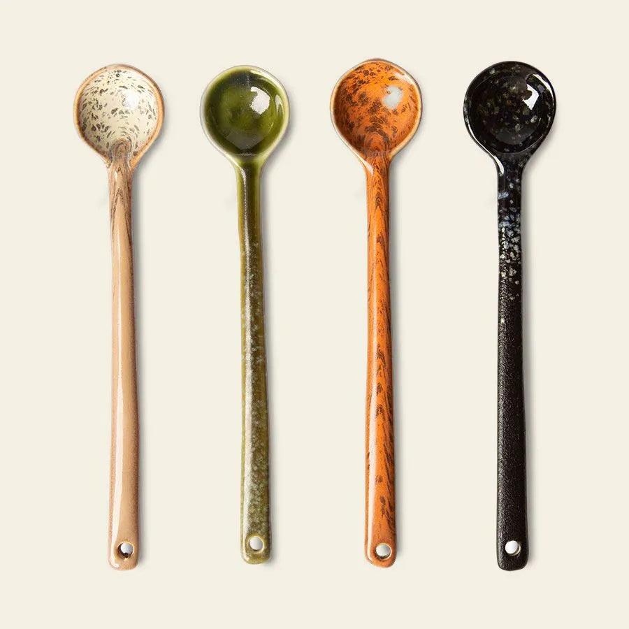The HKLIVING 70s Ceramics: Spoons L, Set of 4 features long-handled ceramic spoons in beige, green, orange, and black with speckled patterns and end holes, capturing a retro 70s vibe.