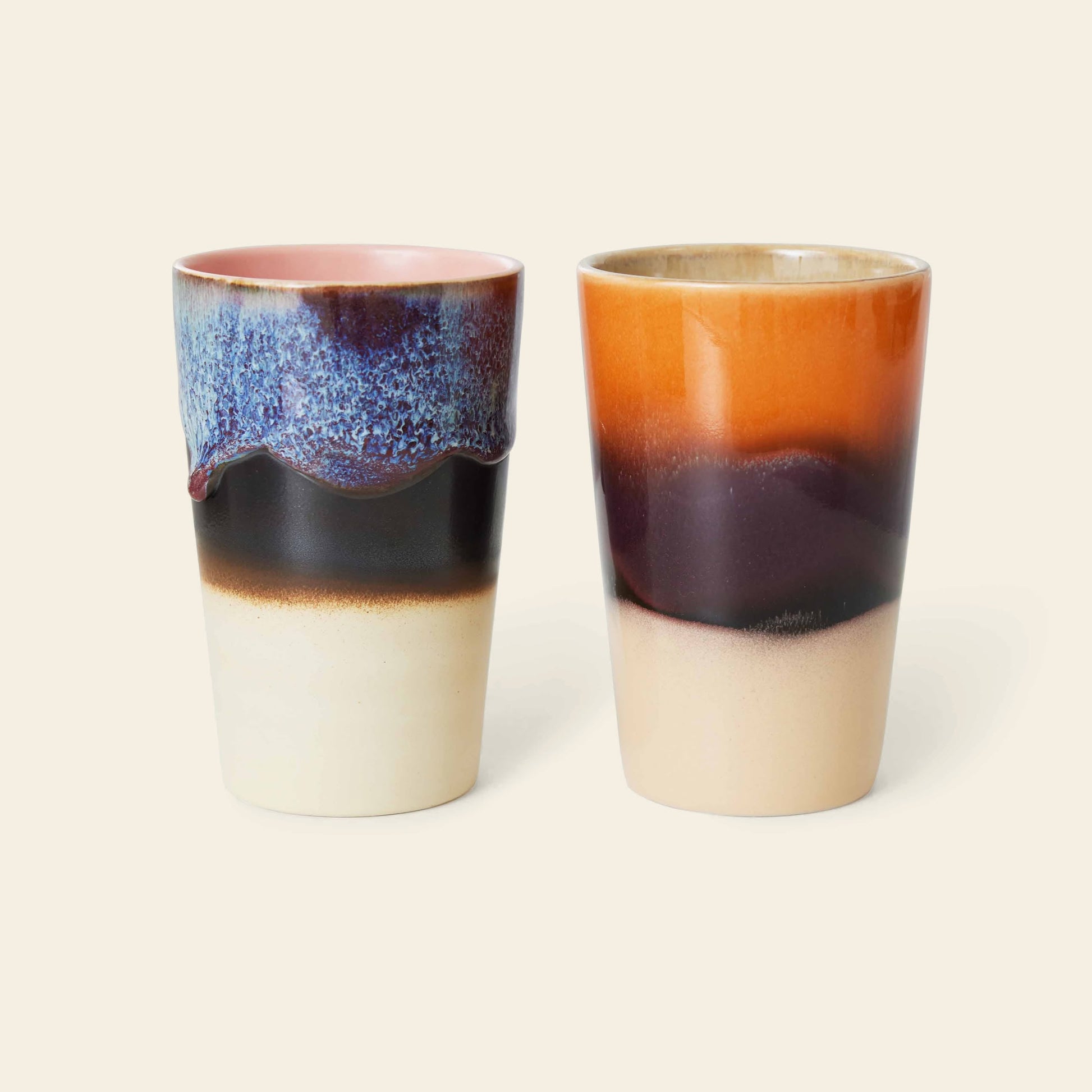 The HKLIVING 70s Ceramics Tea Mugs, Set of 2, feature glossy multicolored glazes: one with blue, purple, and cream wavy patterns near the rim; the other with orange, brown, and cream horizontal bands for a retro look.