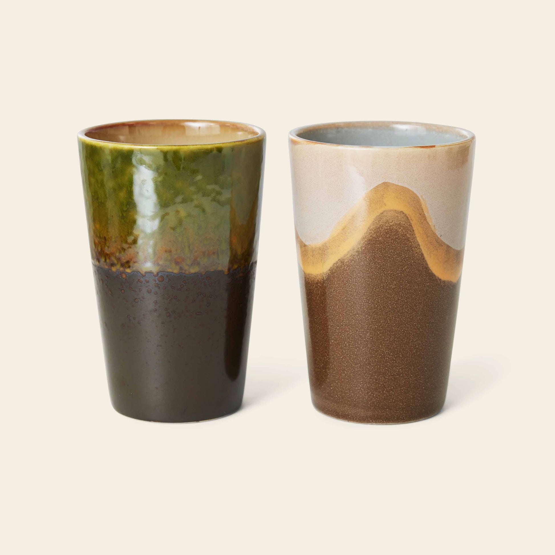HKLIVING 70s Ceramics: Tea Mugs, Set of 2 by HKLIVING feature earthy, handmade looks—one mug glazed green and brown, the other with a brown base plus tan and cream accents—both displayed on a light background.