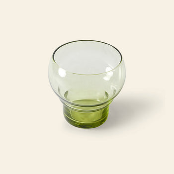 A set of four HKLIVING 70s Glassware Bulb Glasses—round, transparent green glasses with a wide bowl and short base—are displayed against a light beige background.