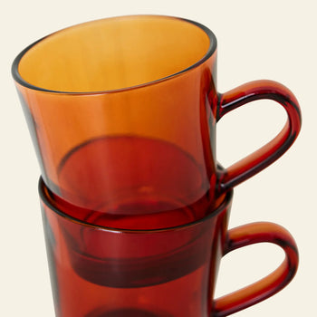 The HKLIVING 70s Glassware Coffee Cups, Set of 4, features translucent orange and deep red cups with curved handles and a retro 70s vibe, stacked stylishly against a light background.