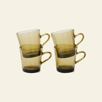 The HKLIVING 70s Glassware Coffee Cups, Set of 4, are stacked in pairs, each amber cup nestled within another, evoking retro style against a plain light beige background.