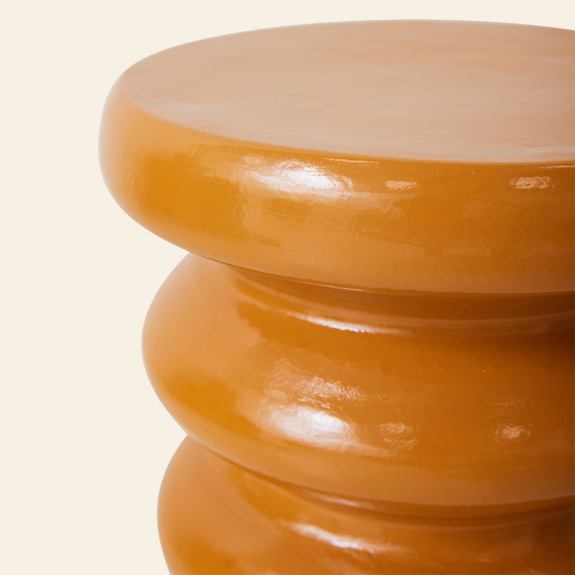 The HKLIVING Allure Side Table by HKLIVING is a glossy, round orange ceramic piece with modern elegance, showcasing a smooth stacked ribbed design and shiny curved surface, viewed at an angle against a pale background.