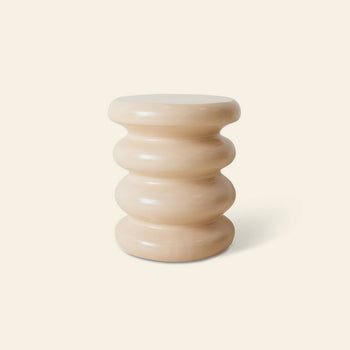 The HKLIVING Allure Side Table by HKLIVING features a beige, sculptural design with stacked ribbed segments and a smooth finish, creating modern elegance against a light cream backdrop.