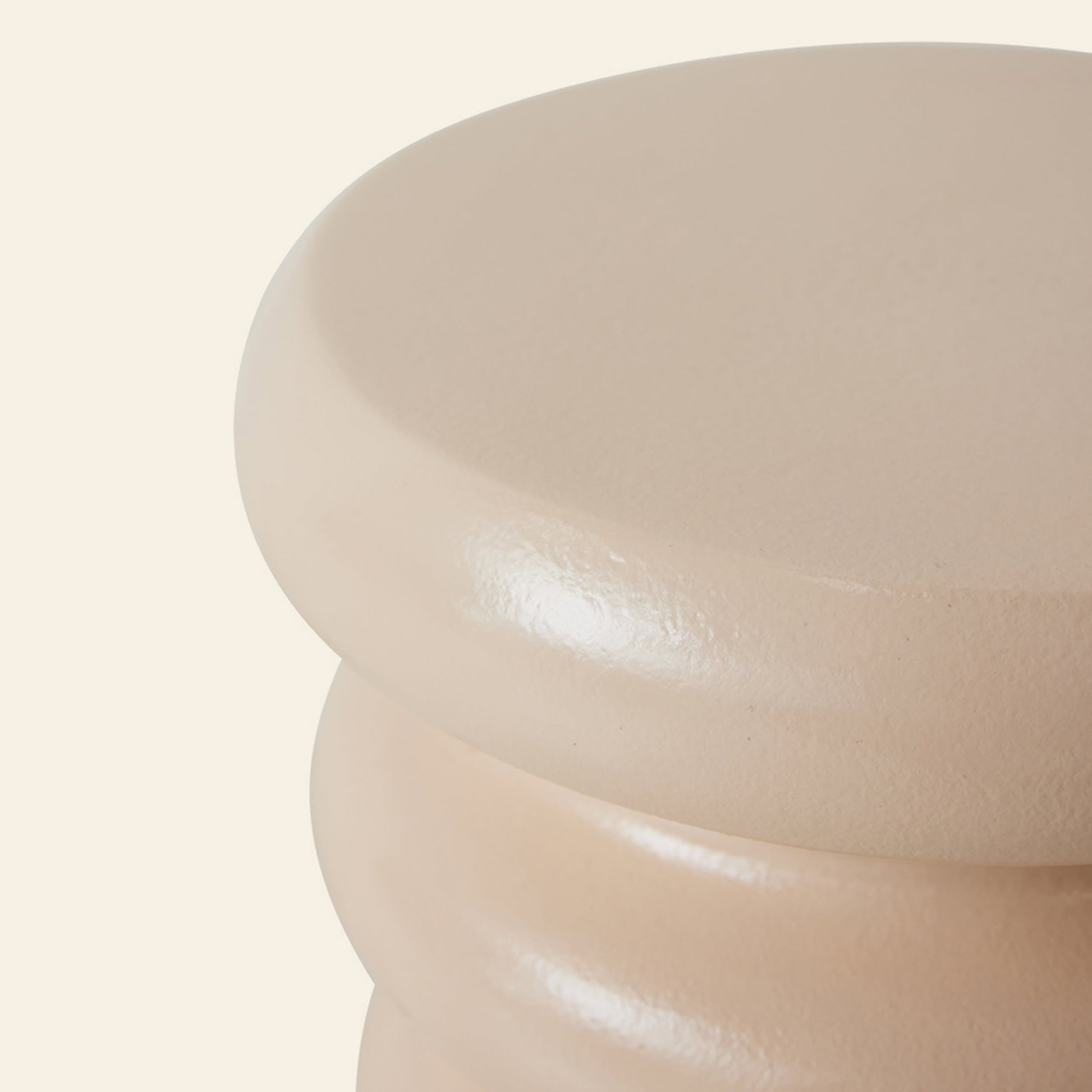 Close-up of the HKLIVING Allure Side Table by HKLIVING, showcasing its smooth, glossy beige finish and stacked ribbed design. Only the top and partial sides are visible against an off-white background, highlighting its modern elegance.