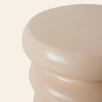 Close-up of the HKLIVING Allure Side Table by HKLIVING, showcasing its smooth, glossy beige finish and stacked ribbed design. Only the top and partial sides are visible against an off-white background, highlighting its modern elegance.